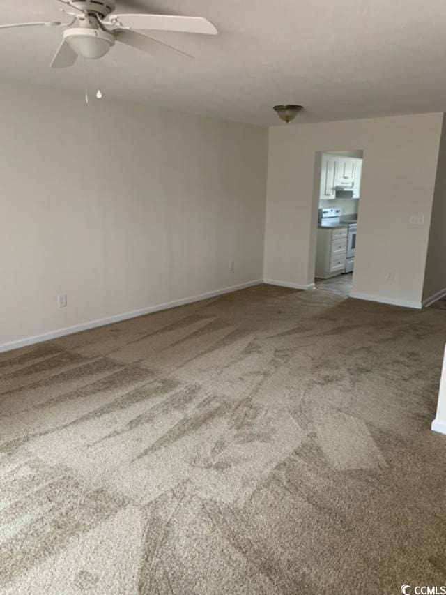 carpeted empty room with a ceiling fan and baseboards