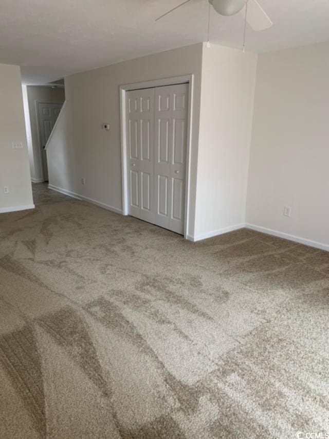 carpeted empty room featuring a ceiling fan and baseboards