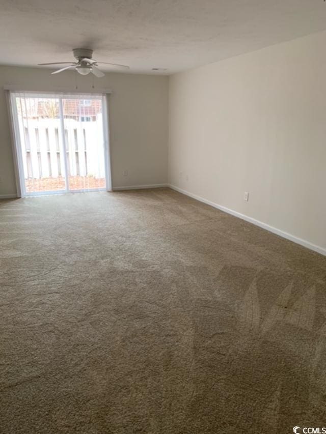 spare room featuring carpet floors, a ceiling fan, and baseboards