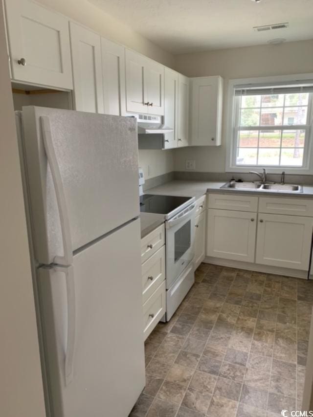 kitchen with visible vents, white appliances, a sink, and white cabinetry