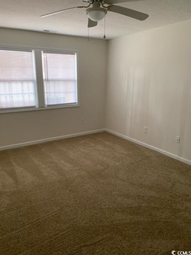 carpeted spare room featuring a ceiling fan and baseboards