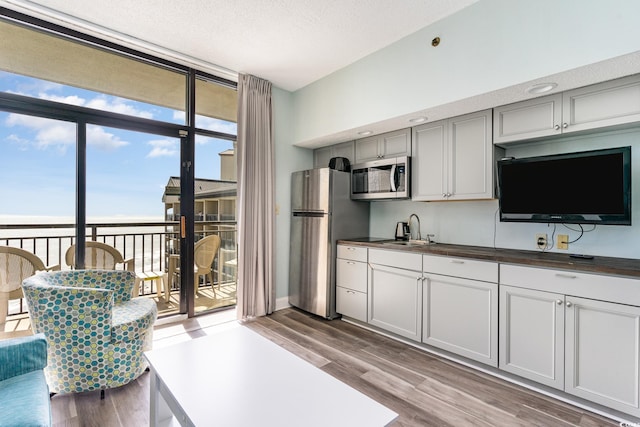 kitchen featuring stainless steel appliances, dark countertops, a sink, and floor to ceiling windows