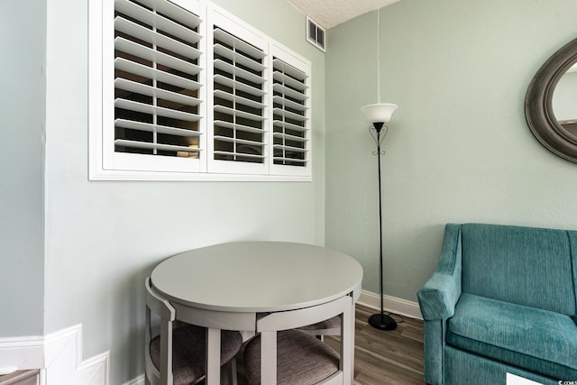 interior space featuring baseboards, a textured ceiling, visible vents, and wood finished floors