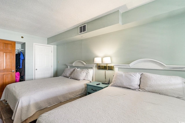 bedroom with a textured ceiling, a spacious closet, a closet, and visible vents