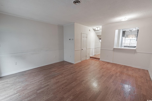 empty room with hardwood / wood-style floors, crown molding, and a textured ceiling