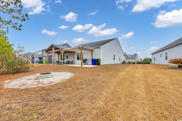 back of house with a patio area, a lawn, a pergola, and a fire pit