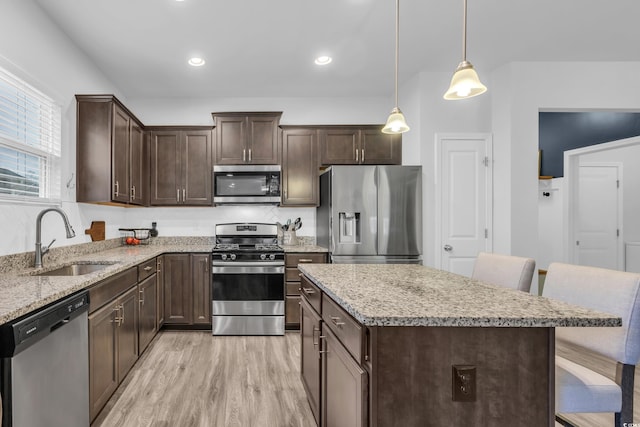 kitchen featuring a kitchen bar, appliances with stainless steel finishes, sink, a center island, and pendant lighting