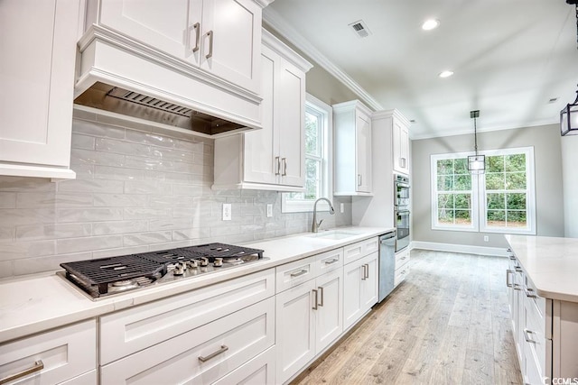 kitchen featuring white cabinetry, custom exhaust hood, ornamental molding, stainless steel appliances, and light wood-style flooring
