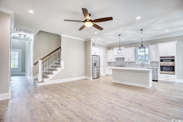 kitchen with decorative backsplash, a center island, white cabinets, a ceiling fan, and appliances with stainless steel finishes