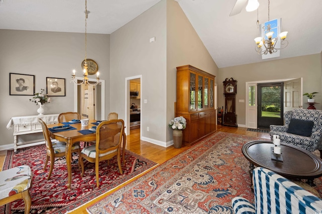 dining area featuring high vaulted ceiling, light wood-type flooring, and an inviting chandelier