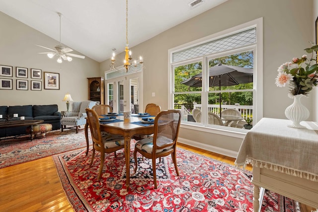 dining area with lofted ceiling, french doors, a notable chandelier, and hardwood / wood-style floors