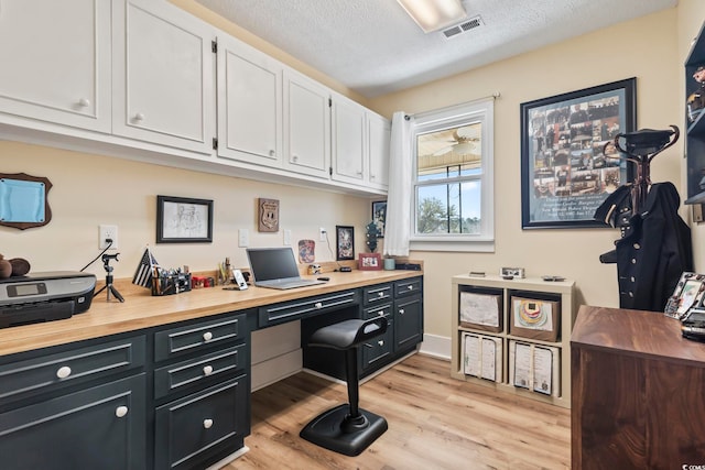 office featuring light hardwood / wood-style floors, built in desk, and a textured ceiling