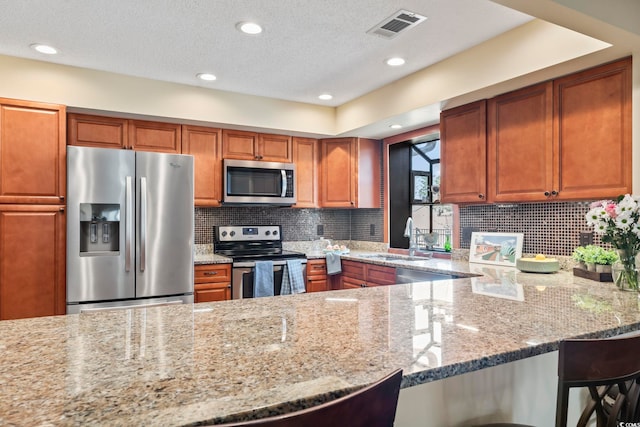 kitchen featuring a breakfast bar area, appliances with stainless steel finishes, sink, and light stone counters