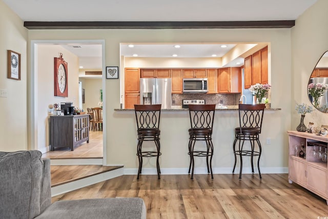 kitchen featuring a kitchen breakfast bar, tasteful backsplash, stainless steel appliances, and kitchen peninsula