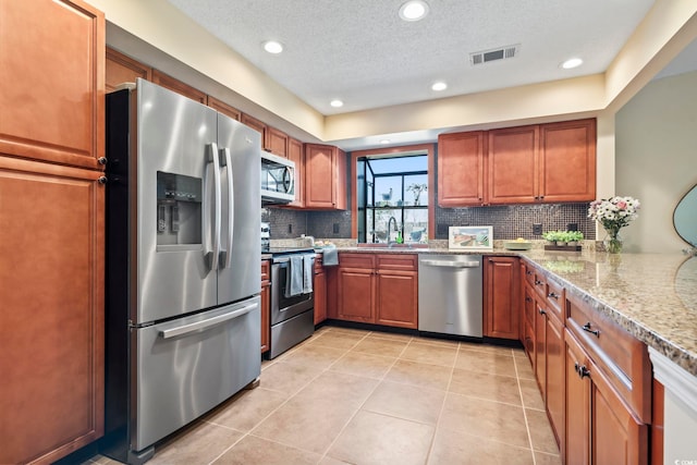 kitchen with light tile patterned floors, tasteful backsplash, stainless steel appliances, and light stone countertops