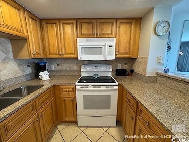 kitchen featuring light tile patterned floors, white appliances, tasteful backsplash, and brown cabinetry