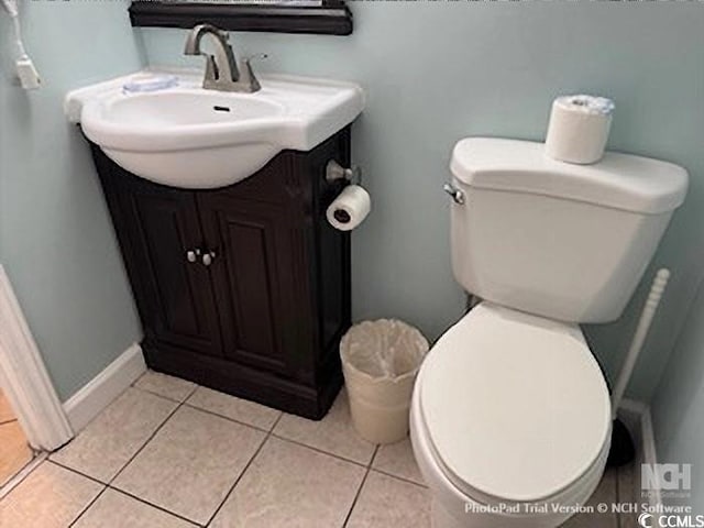 half bath with vanity, toilet, baseboards, and tile patterned flooring