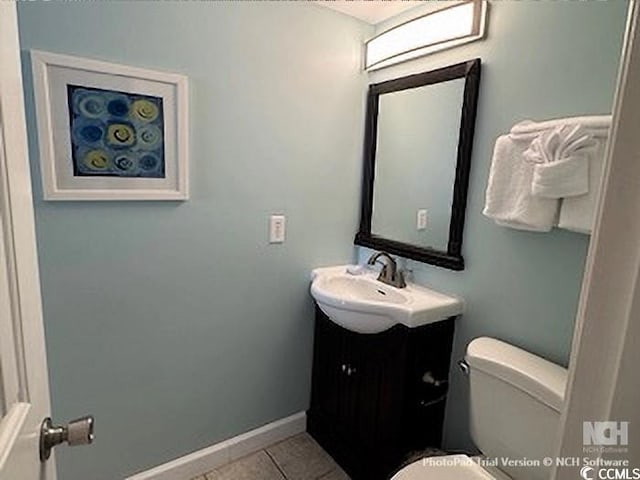 half bathroom with tile patterned flooring, toilet, vanity, and baseboards