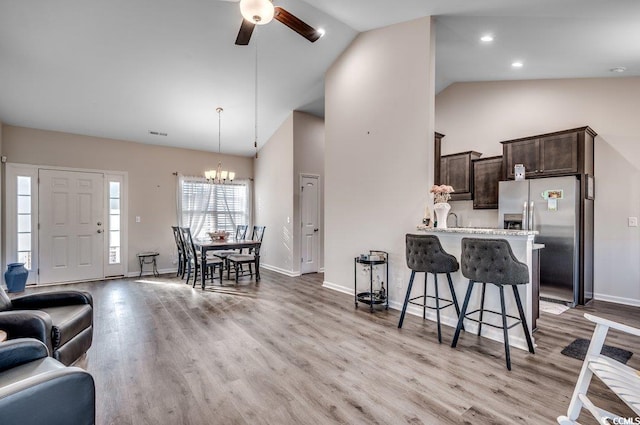 kitchen featuring stainless steel refrigerator with ice dispenser, a breakfast bar, dark brown cabinets, light wood-type flooring, and kitchen peninsula