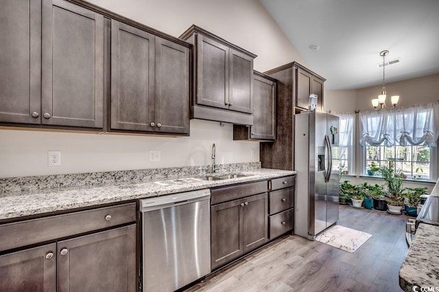 kitchen with dark brown cabinetry, sink, light wood-type flooring, appliances with stainless steel finishes, and light stone countertops