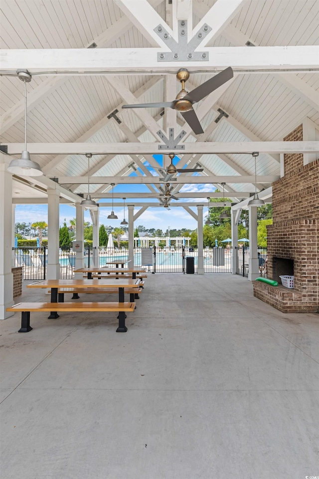 view of patio / terrace featuring an outdoor brick fireplace, fence, and a ceiling fan