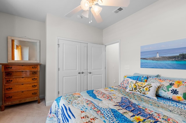 carpeted bedroom with a water view, ceiling fan, visible vents, and a closet