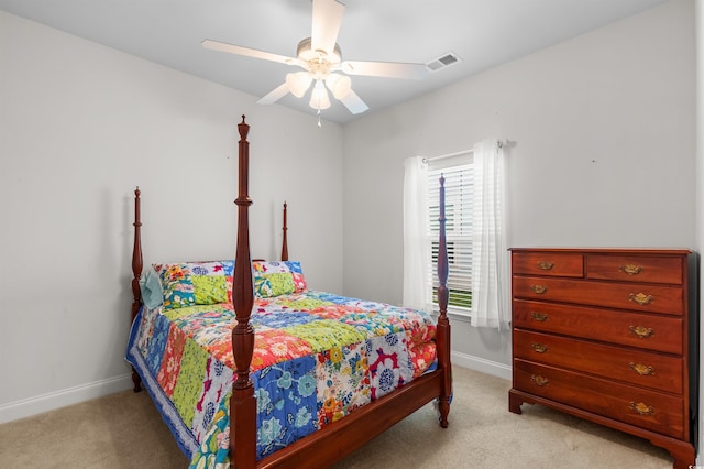 bedroom with light colored carpet, ceiling fan, visible vents, and baseboards