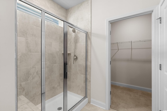 full bath featuring a stall shower, baseboards, and a walk in closet