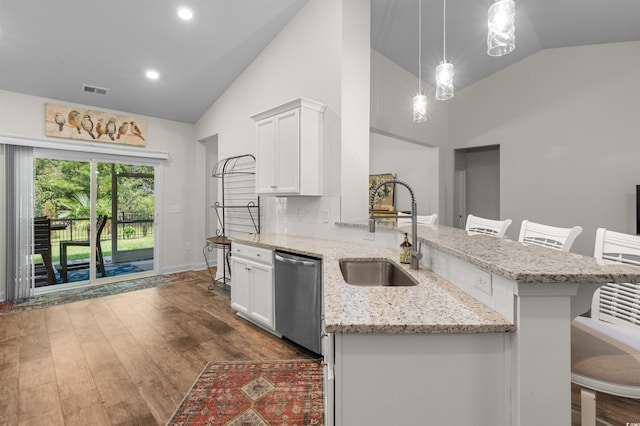 kitchen featuring dark wood finished floors, dishwasher, a sink, and a breakfast bar area