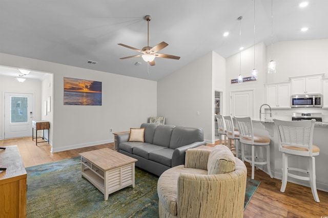 living room with high vaulted ceiling, wood finished floors, visible vents, and a ceiling fan