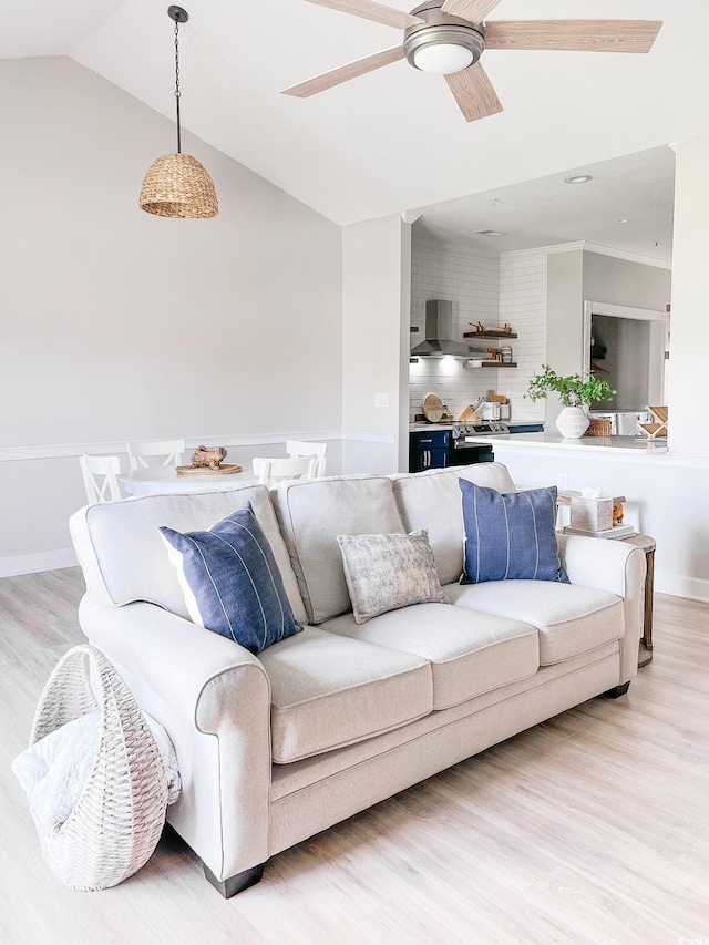 living area featuring baseboards, light wood-style flooring, a ceiling fan, and lofted ceiling