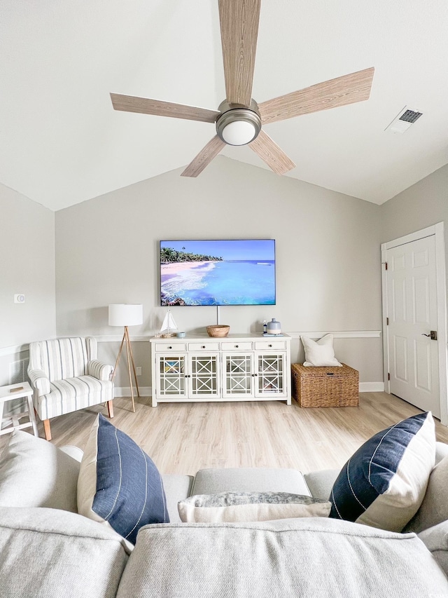 living area with vaulted ceiling, visible vents, and wood finished floors