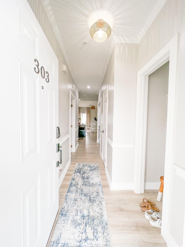 corridor featuring light wood-type flooring and crown molding