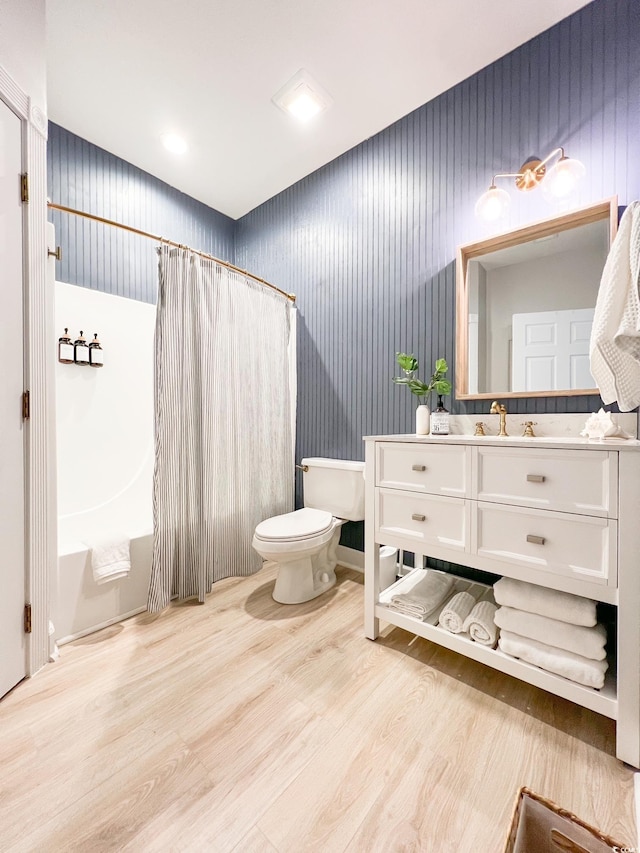 bathroom with vanity, toilet, shower / tub combo, and wood finished floors