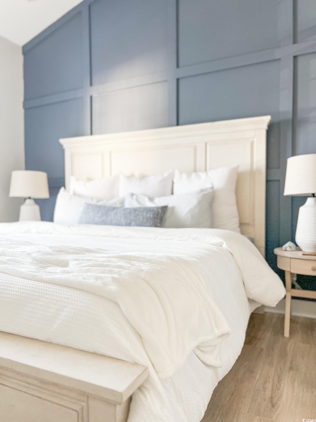 bedroom featuring a decorative wall and light wood-style floors