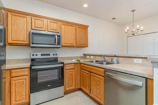 kitchen featuring pendant lighting, stainless steel appliances, a chandelier, and sink