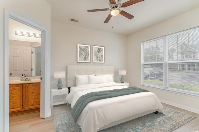 bedroom with multiple windows, ensuite bath, light hardwood / wood-style floors, and ceiling fan