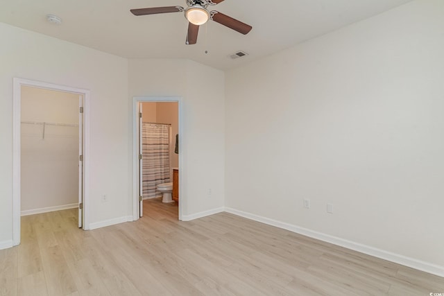 unfurnished bedroom with connected bathroom, a walk in closet, ceiling fan, light hardwood / wood-style floors, and a closet