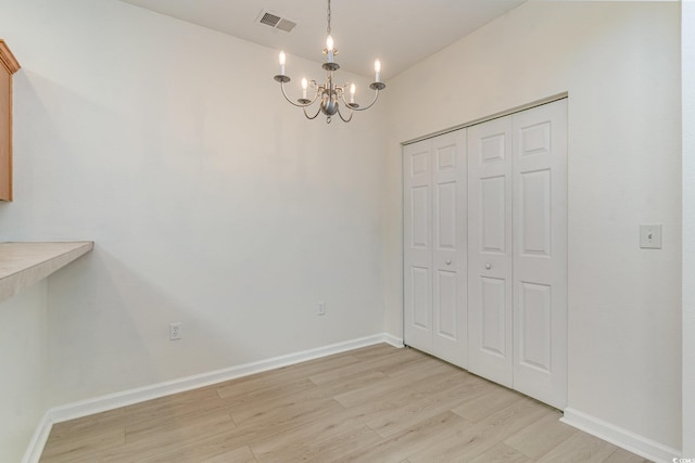 unfurnished dining area featuring a chandelier and light wood-type flooring