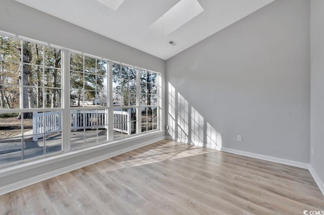 spare room with wood-type flooring, plenty of natural light, and lofted ceiling with skylight