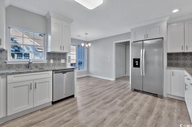 kitchen featuring sink, light hardwood / wood-style flooring, appliances with stainless steel finishes, light stone countertops, and white cabinets