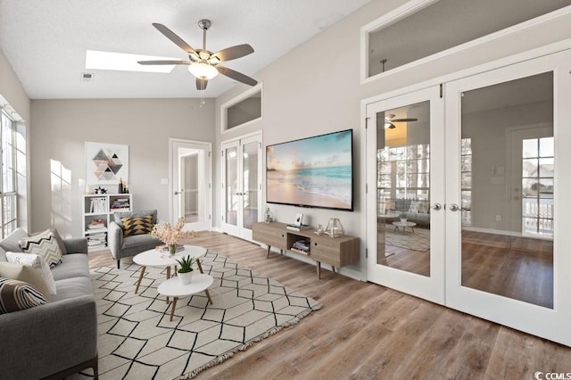 living room with wood-type flooring, high vaulted ceiling, ceiling fan, and french doors