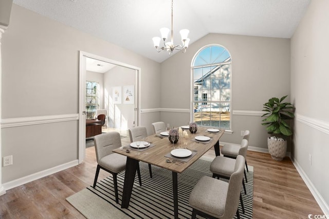 dining area featuring lofted ceiling, a chandelier, and light hardwood / wood-style flooring