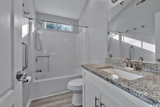 full bathroom with toilet,  shower combination, wood-type flooring, a textured ceiling, and vanity