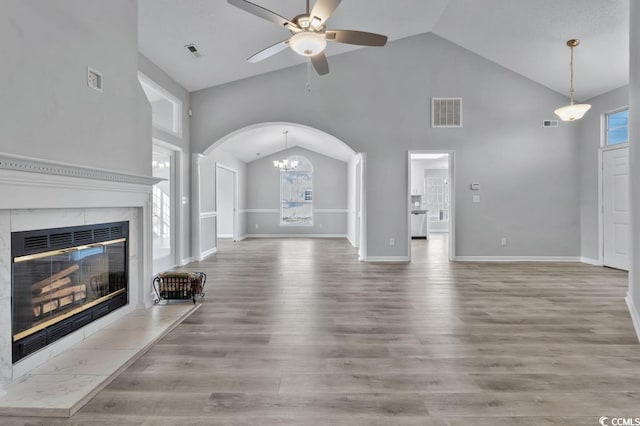 unfurnished living room featuring hardwood / wood-style flooring, a premium fireplace, high vaulted ceiling, and ceiling fan