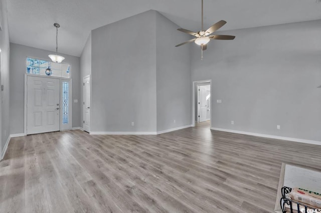 foyer with ceiling fan, a towering ceiling, and light wood-type flooring
