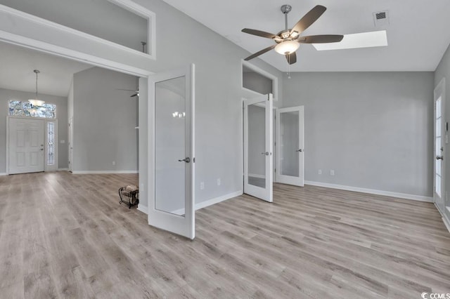 interior space with french doors, lofted ceiling, ceiling fan with notable chandelier, and light hardwood / wood-style flooring