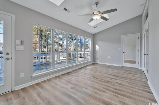 spare room featuring ceiling fan, lofted ceiling with skylight, and light hardwood / wood-style flooring