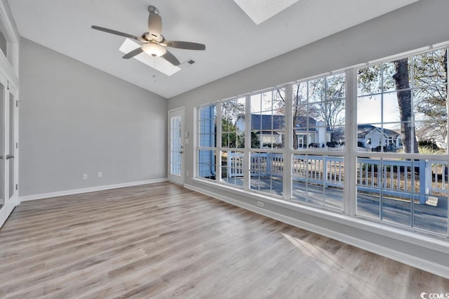 spare room featuring ceiling fan, hardwood / wood-style flooring, and vaulted ceiling with skylight