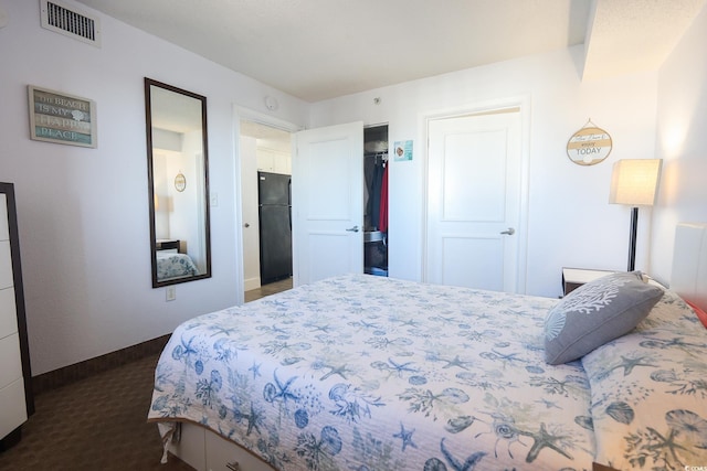 bedroom with black refrigerator and dark colored carpet